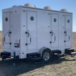 image displays a portable restroom trailer, likely a 4-station unit, designed to provide temporary restroom facilities for events or job sites